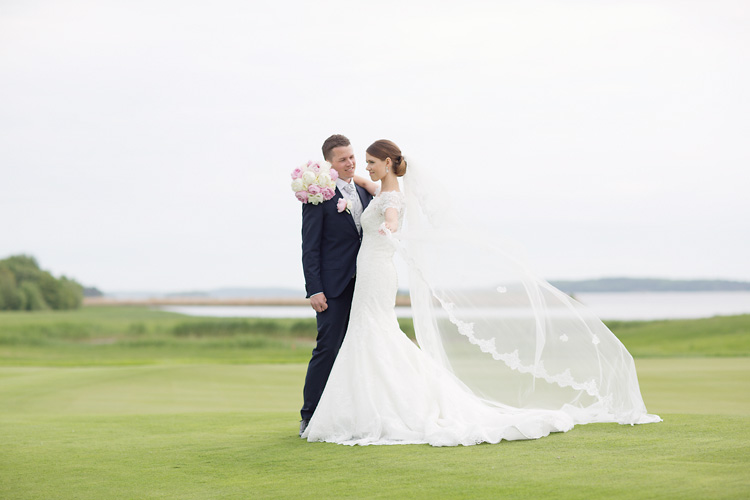 Bröllopsfotografering med lång slöja på golfbana